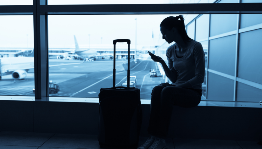 ragazza seduta in aeroporto controlla il cellulare